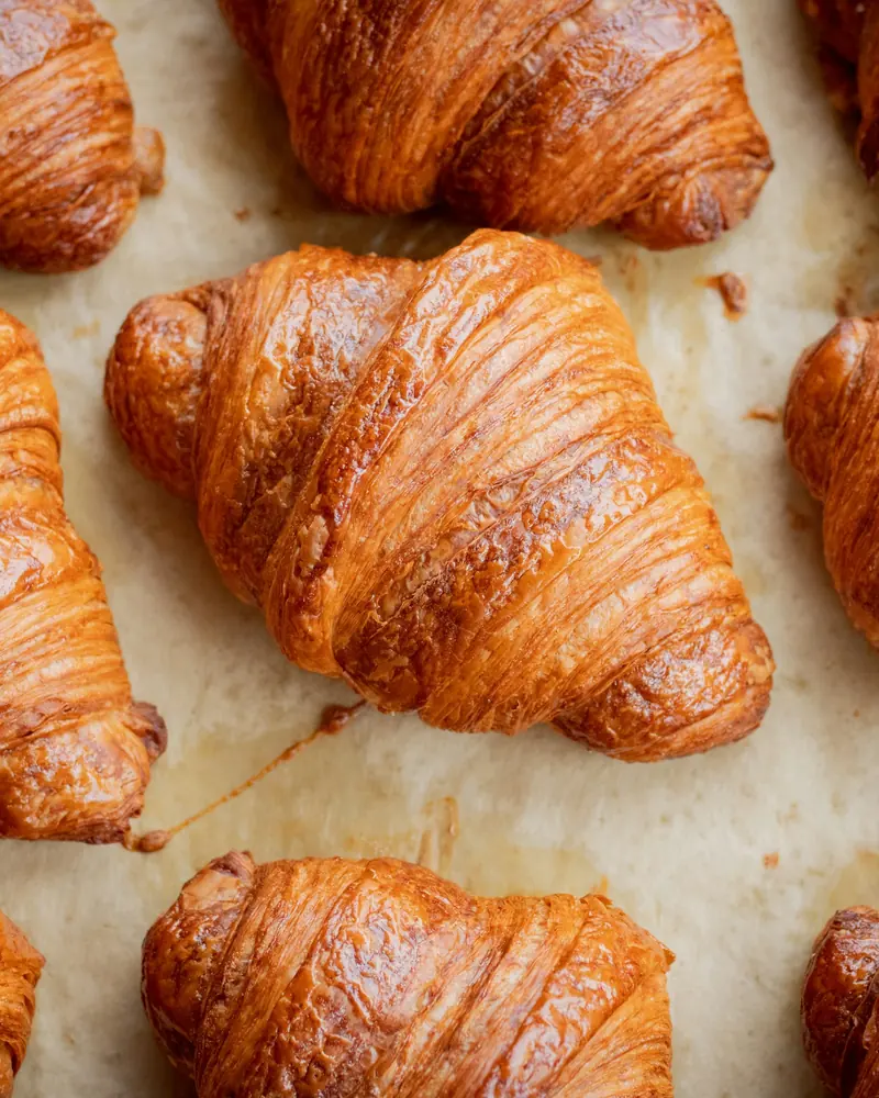 Croissants dourados sobre papel-manteiga (imagem ilustrativa)